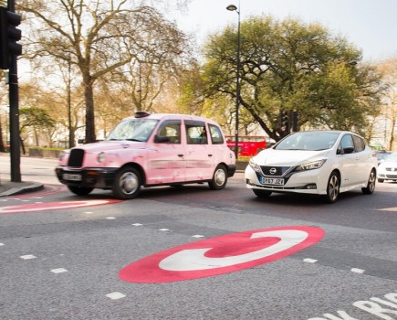 A taxi and a Nissan Leaf driving through London.