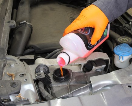 Someone adding coolant into a car's reservoir