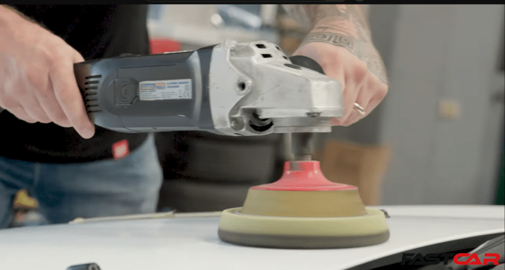 man using a machine polisher on a car bonnet